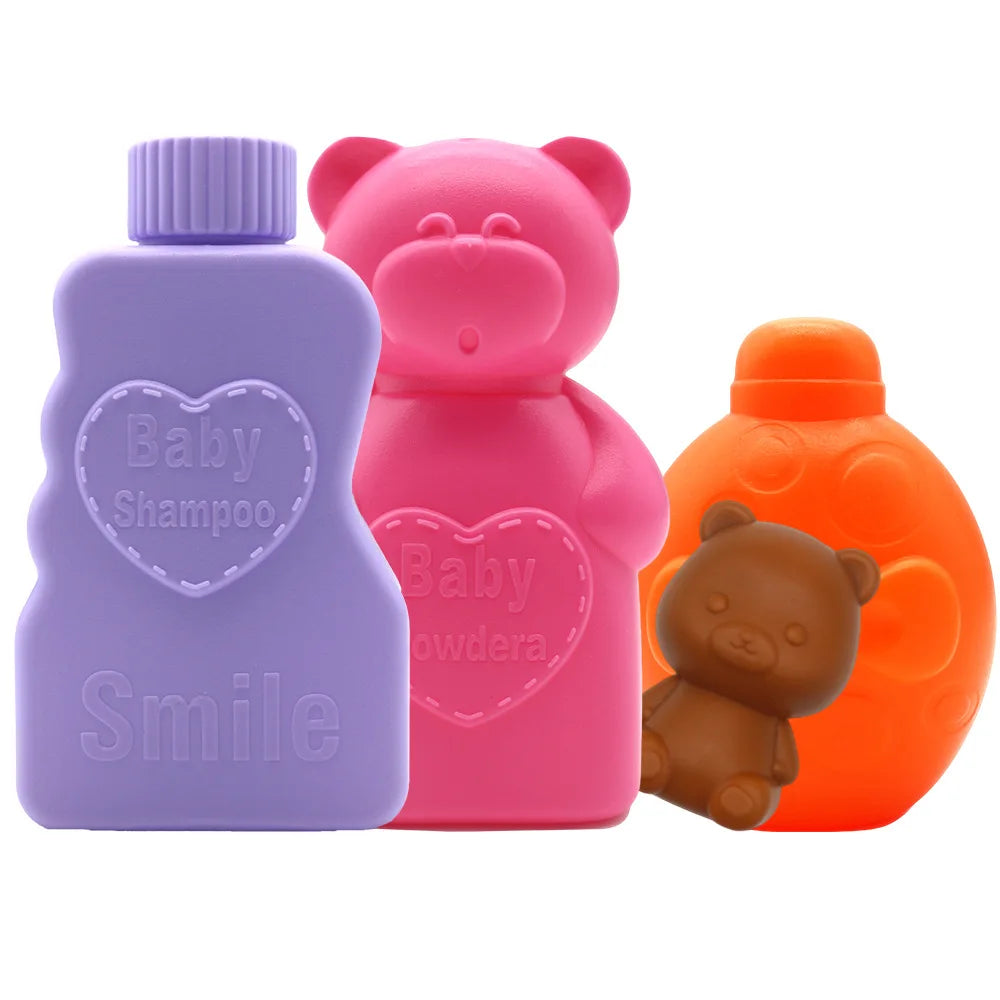 A set of baby shampoo and powder bottles in purple and pink, with a brown teddy bear figure.