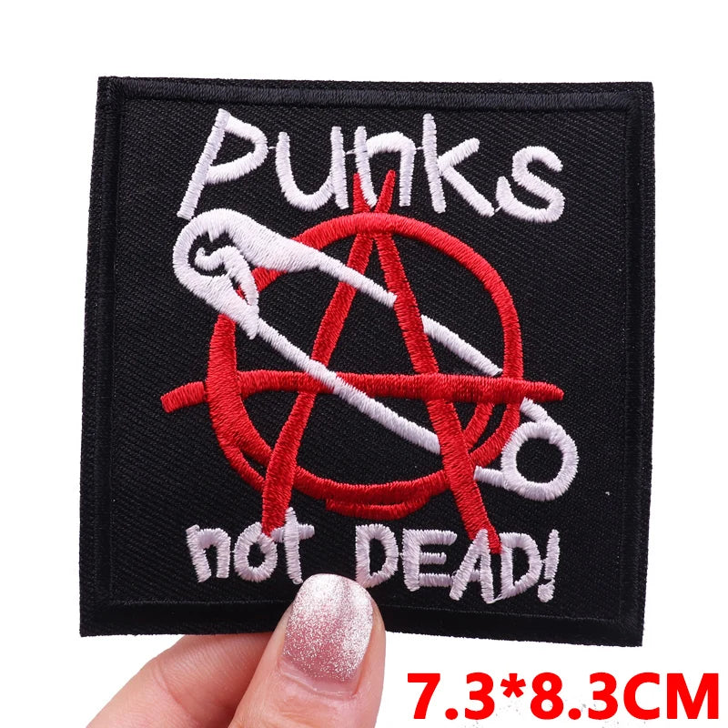 Black embroidered patch featuring a punk aesthetic with a skull and crossbones design in red and white thread