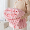 A person is holding a fluffy pink brushed flannel throw blanket with vertical ribbed texture.