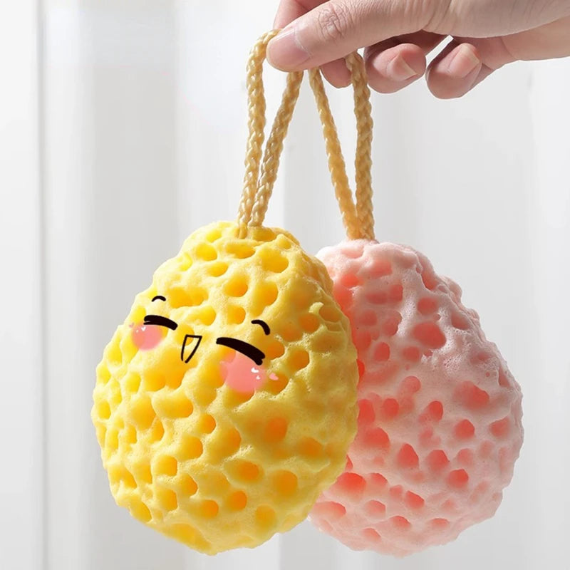 A hand is holding a yellow, squishy mesh bath sponge ball and a pink, squishy mesh bath sponge ball.