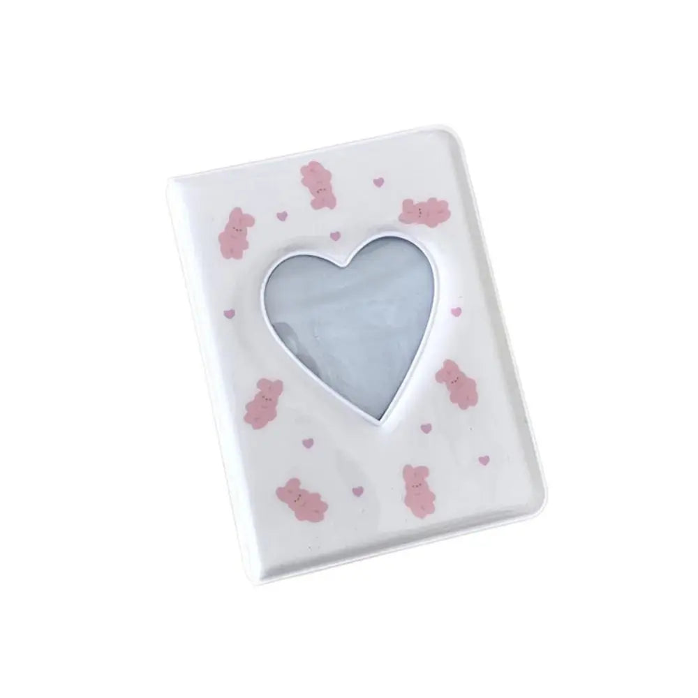 A white photo album cover with a heart cutout and small pink bear decorations.
