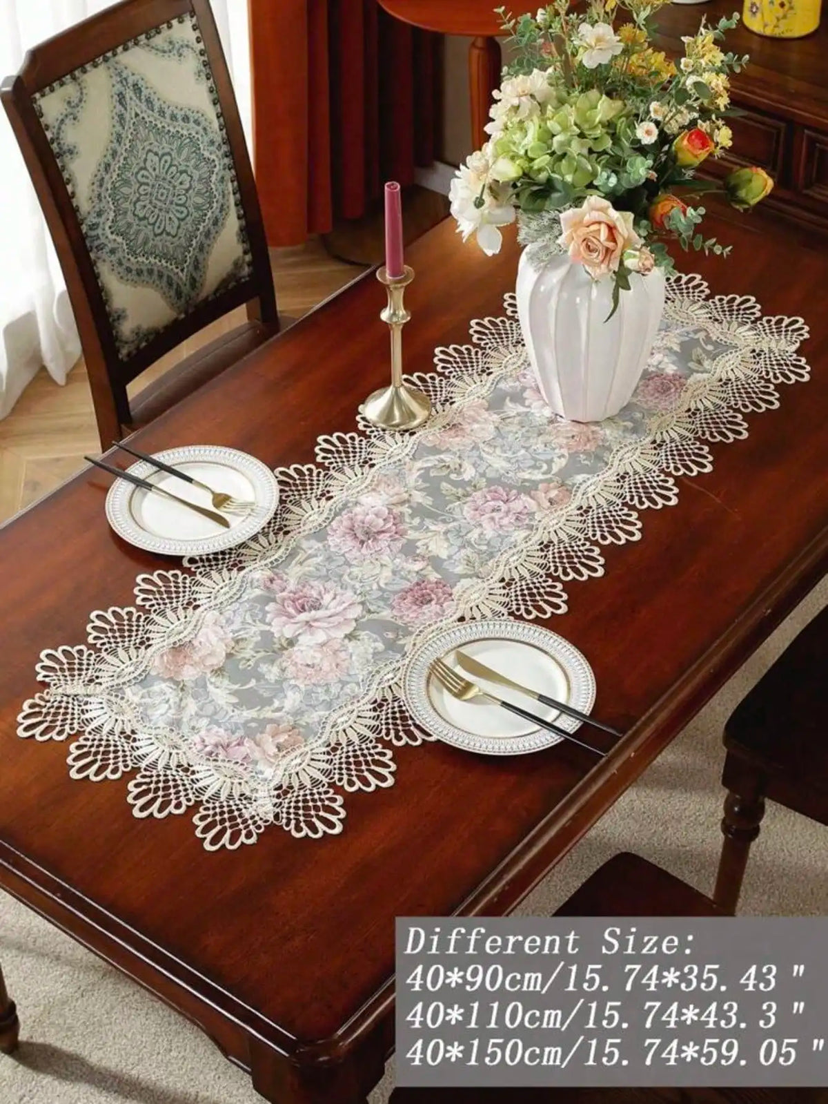 A lace table runner with a floral pattern is displayed on a wooden table set for an elegant meal.