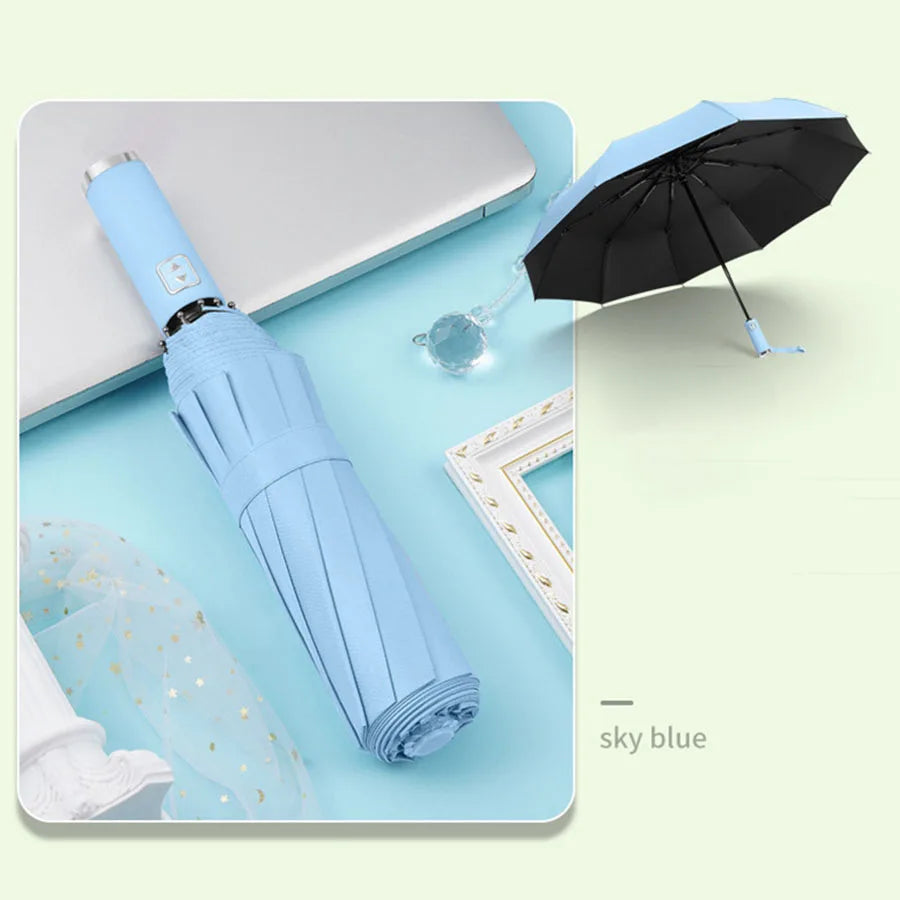 A sky blue automatic foldable umbrella with a black canopy and windproof frame is shown next to a white laptop.