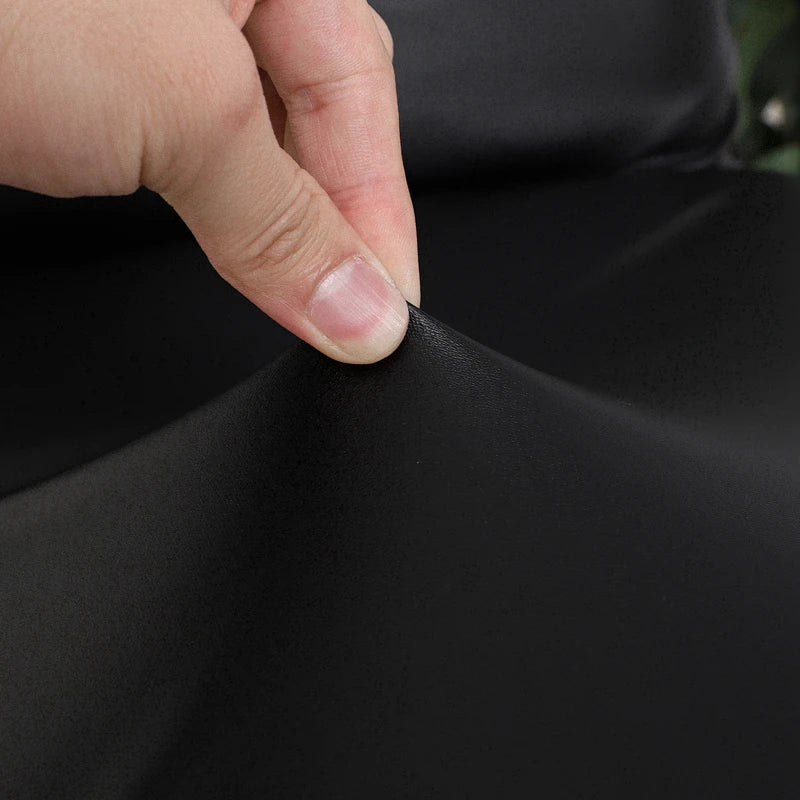 A hand is touching the elastic edge of a black waterproof PU stretch bench cover fabric.