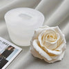 Un pot de bougie en verre blanc et une rose crème réaliste sont présentés sur un tissu clair.