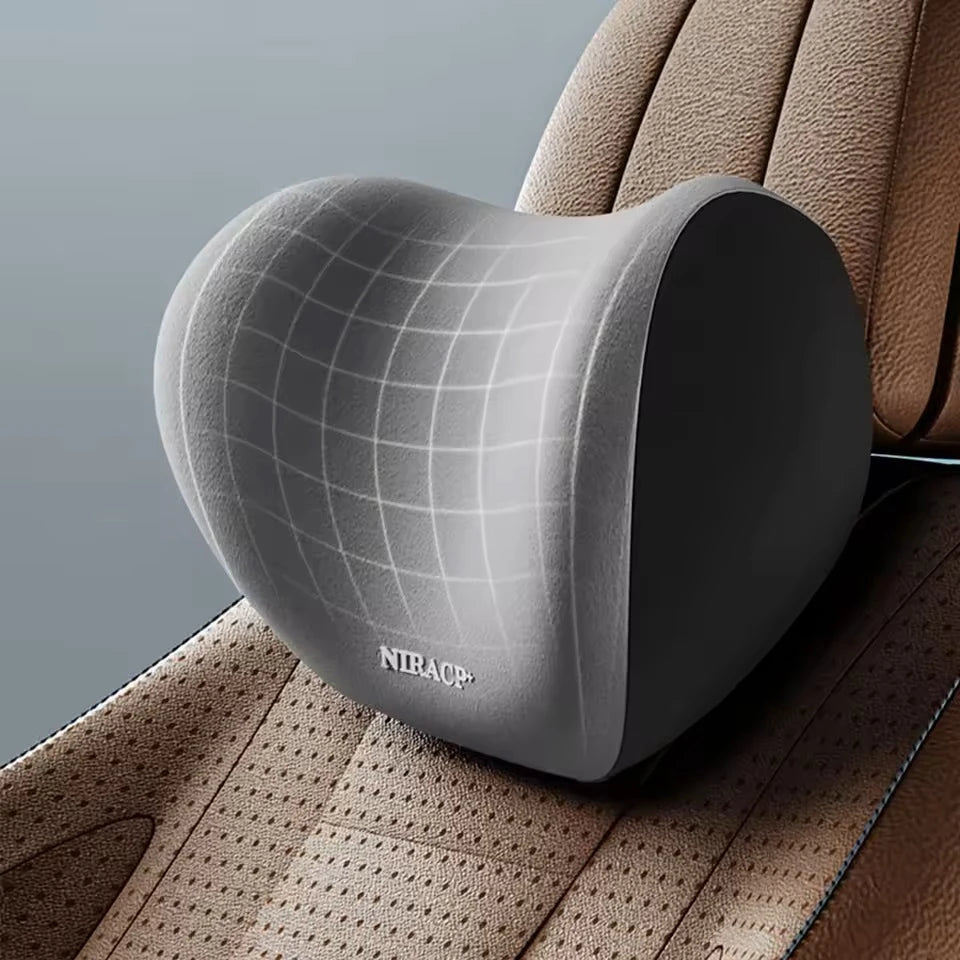 A gray memory foam car headrest and lumbar support pillow resting on a tan leather seat.