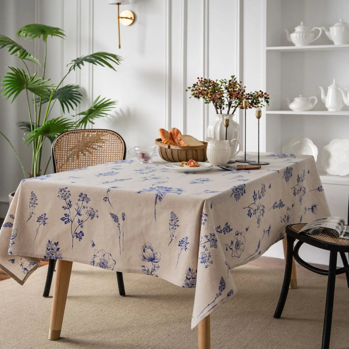 A beige cotton-linen tablecloth featuring a blue rustic fern print on a wooden table.