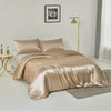 A luxurious champagne silk duvet cover set displayed on a bed in a bright room with a gold floor lamp.