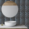 A white bowl sits on a light marble countertop against a dark mosaic tile wall.