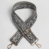 A close-up of an adjustable wide paisley jacquard bag strap in gray and white patterns.
