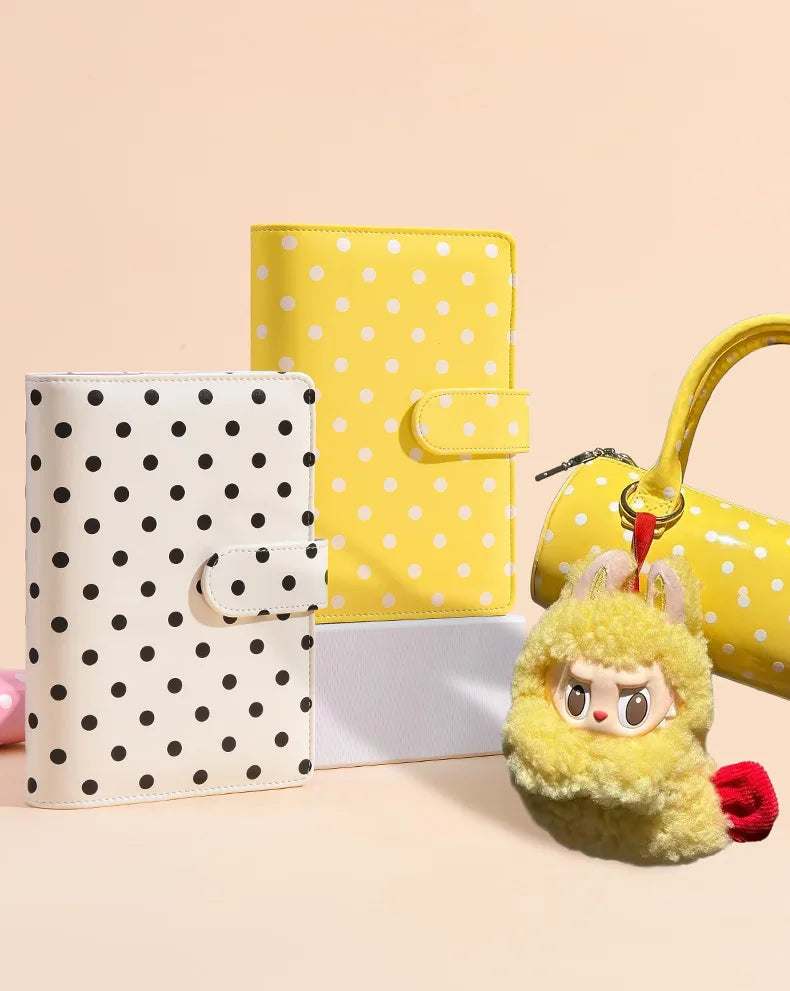 A yellow polka dot PU leather binder wallet with cash envelopes and card holder next to a white gift box.
