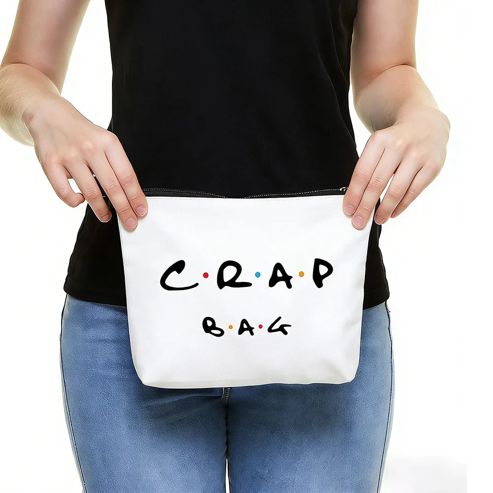 A person holds a white toiletry bag with black text that reads CRAP BAG.