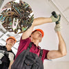 A worker in a red shirt is using a power tool to install heavy duty self-drilling drywall anchors.