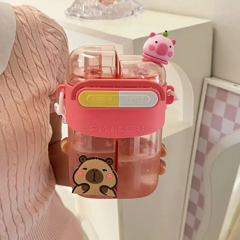 Eine rosa Cartoon-Capybara trinkt aus einer Wasserflasche mit Strohhalm, die von einer Person gehalten wird.