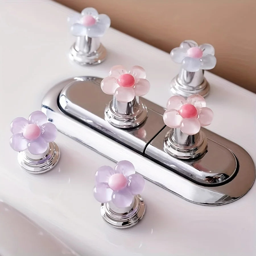 A silver toilet flush handle with pink floral buttons is shown on a white surface.