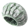 A light green and white tropical leaf patterned satin-lined waterproof shower cap for hair protection.