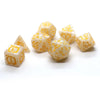A set of ten dragon-embellished polyhedral dice in a pale yellow or ivory color scattered on a white surface.