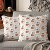 White ghost and pumpkin patterned throw pillow cover on a gray sofa.