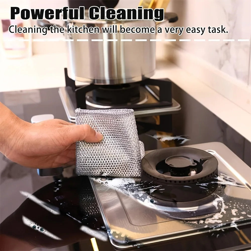 A hand is using a double-layer microfiber cleaning cloth to wipe down a black cooking surface.