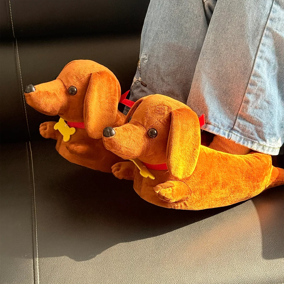 Two orange plush cartoon dachshund dogs wearing red and yellow collars resting on a dark surface.