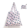 A reusable shopping tote bag featuring a pink and blue tropical leaf pattern, shown with an attached carry pouch.