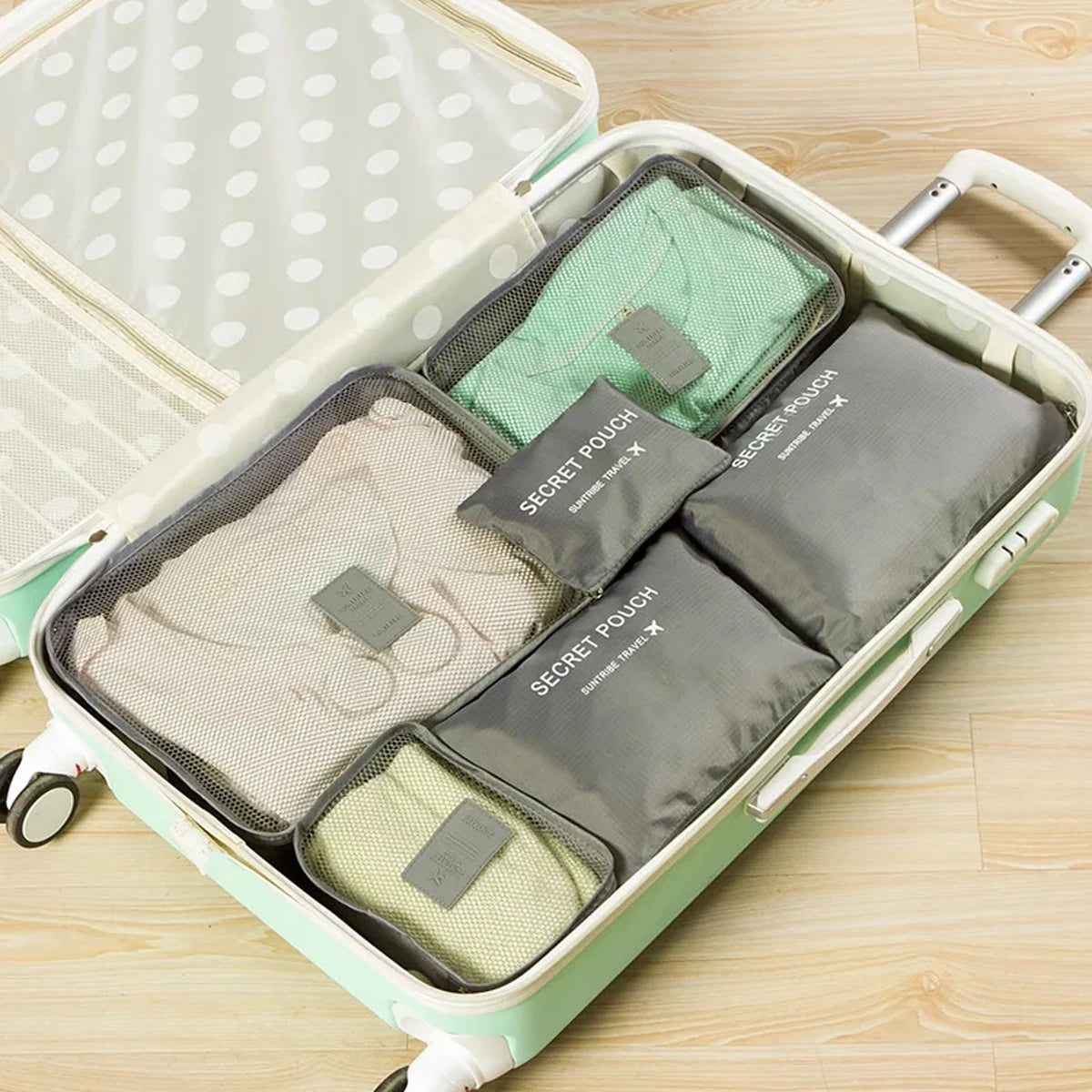 A light green packing cube set with six zippered pouches is displayed inside the open storage box.