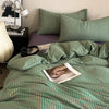A green and white striped duvet cover set with matching pillows on a bed.
