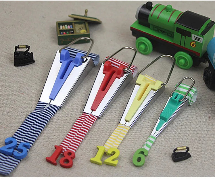 A set of four stainless steel bias tape makers with different sized metal clips and colored tapes.