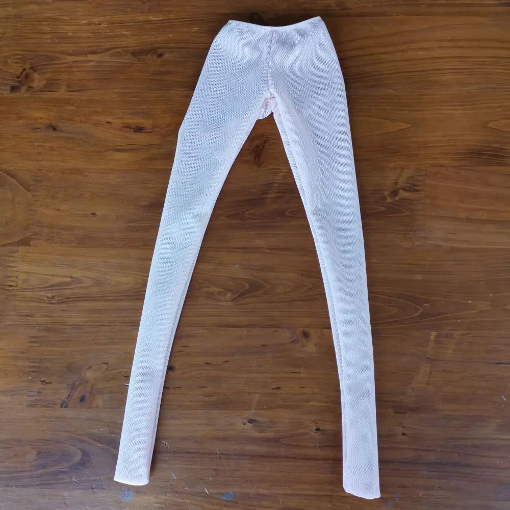 A pair of light pink or beige sheer stockings with a visible seam at the crotch, laid flat on a wooden surface.