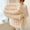 A fluffy beige flannel blanket is draped over a person's arm, showcasing its thick texture and soft appearance.