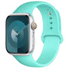 A silver Apple Watch encased in a light mint green silicone sport band.