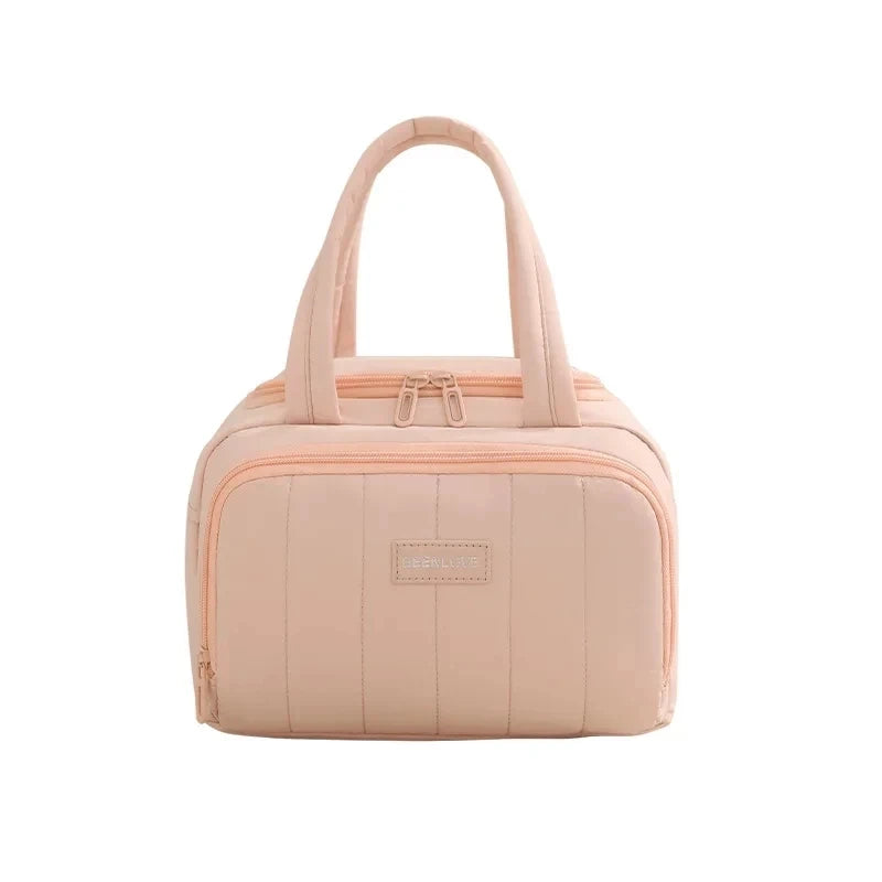 A light pink insulated quilted lunch tote bag with a flap closure.