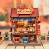 A detailed miniature kit of a Japanese house featuring a traditional roof and storefront, complete with wooden elements and l