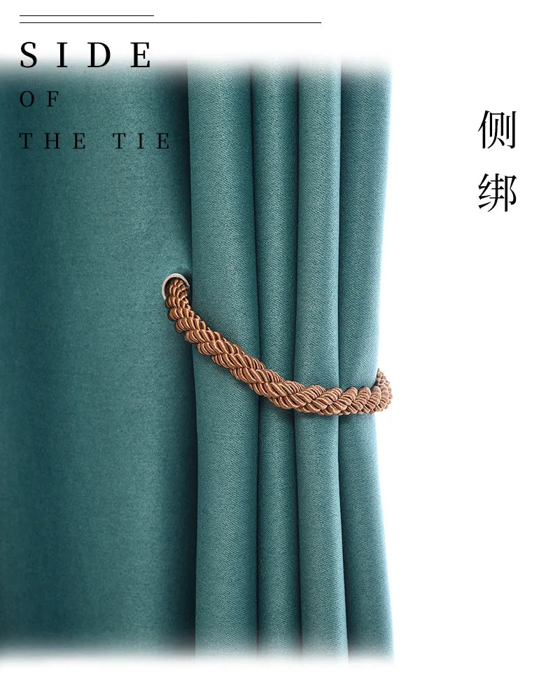 A close-up of a teal curtain fabric with a natural rope tieback in the center.