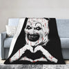 A black and white illustration of a clown face with blood dripping, printed on a coral fleece throw blanket.