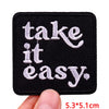 Black embroidered iron-on letter patch with white text that reads take it it easy