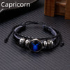 A black leather wrap bracelet featuring a blue glow charm and silver accents.
