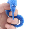A hand holds a bright blue, fuzzy caterpillar trick with large eyes.