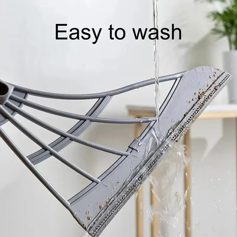 A silicone squeegee broom with a long adjustable handle is shown being washed under running water.