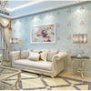 Elegant living room featuring a light blue floral wallpaper, a sofa, and decorative glass tables.