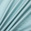 A close-up of a flowing, light mint green bamboo flat sheet fabric draped softly.