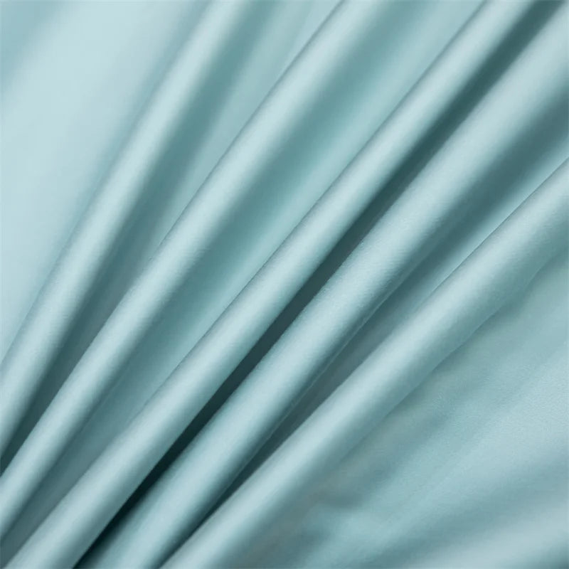 A close-up of a flowing, light mint green bamboo flat sheet fabric draped softly.
