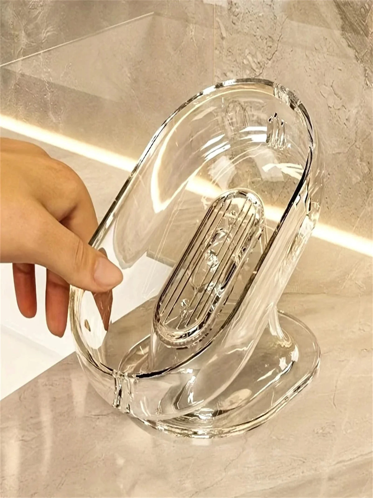 Eine Hand hält eine elegante, klare Glasseife-Schale mit gegossener Form auf einer Marmoroberfläche.
