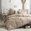 A beige duvet cover set with a pom-pom trim displayed on a bed in a bright room.