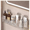 A clear wall-mounted storage basket with a water ripple design holding various personal care products like perfume and cosmet