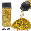 A glass jar of holographic chunky nail glitter mix with a black shaker top next to a pile of loose glitter.