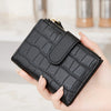 A hand holds a black quilted zippered wallet with card slots and coin pocket.