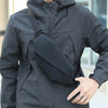 A man wearing a gray waterproof jacket with a black waist pack, posing outdoors.