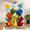 A colorful throw blanket featuring five cartoon dinosaurs and a sunny sky design.