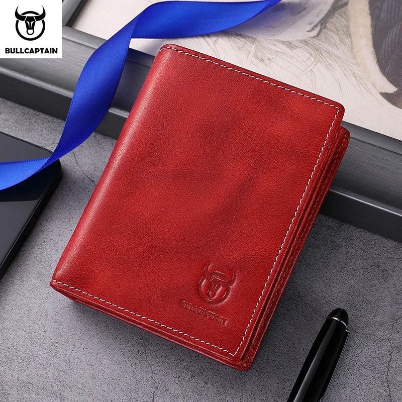 A red genuine leather men's bifold wallet with stitching and a blue ribbon displayed on a gray surface.